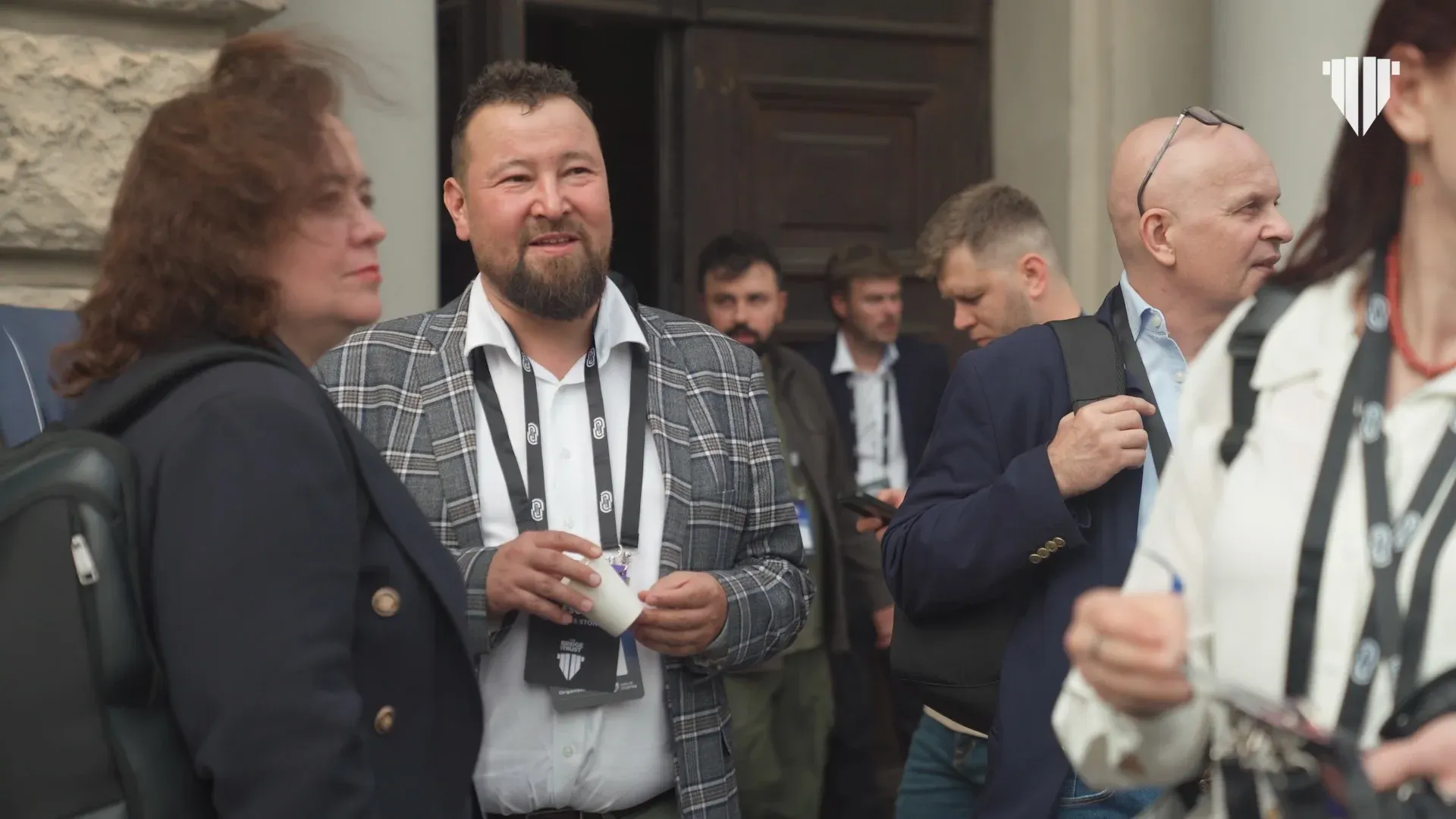 Investors and founders talking outside a building in Lviv, wearing event lanyards.