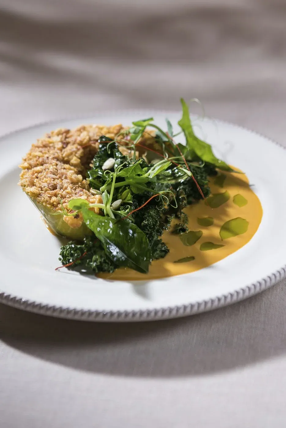 A plated dish with greens and a golden sauce from the Solein tasting in Singapore, 2023.